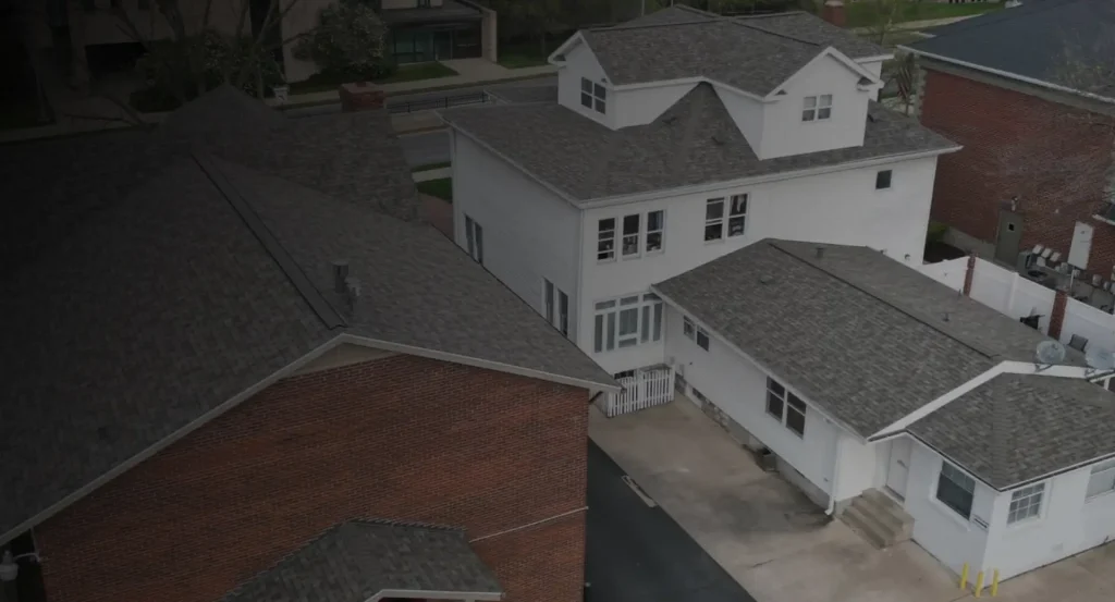A white multi-story house with new shingles from Resolve Roofing
